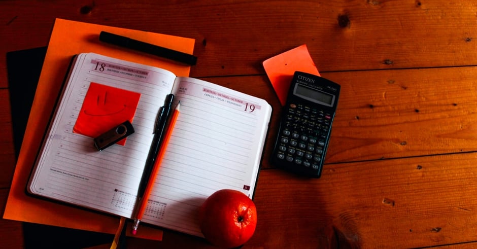 Red notebook and calculator with an apple