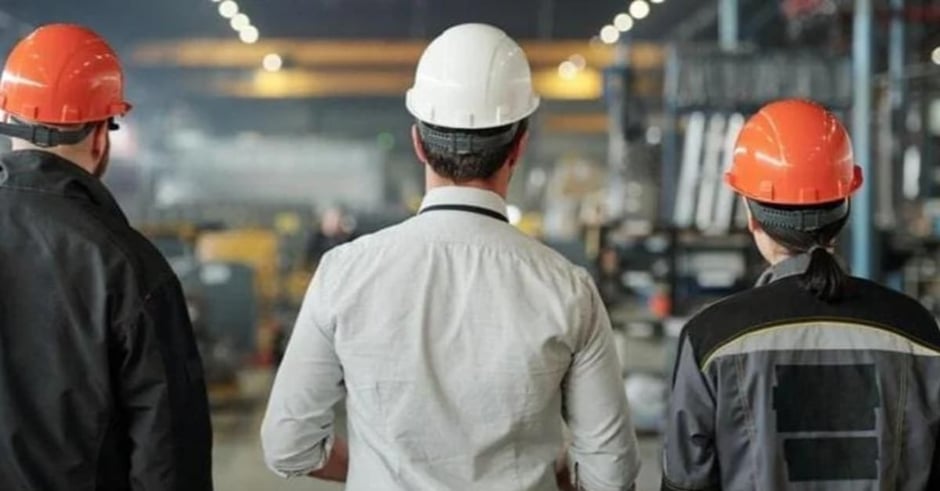 Three men with hard hats in a warehouse