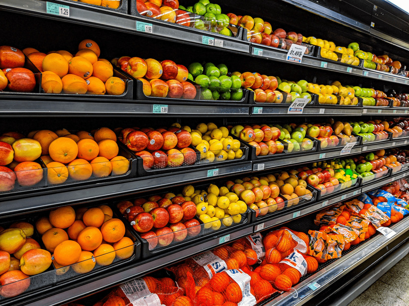 An image of shelves of fruits such as oranges and apples