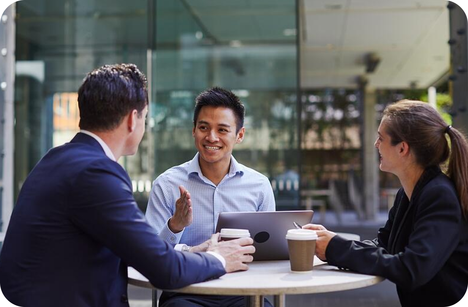 Three workers sitting at a table outside