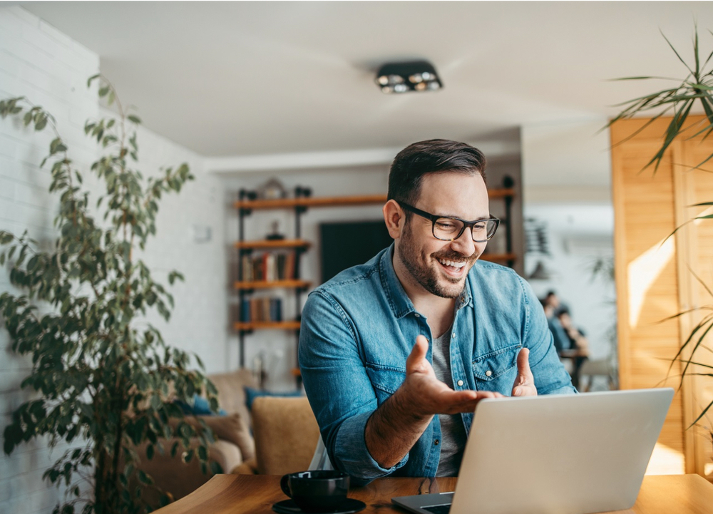 Man with glasses pointing and smiling at his laptop