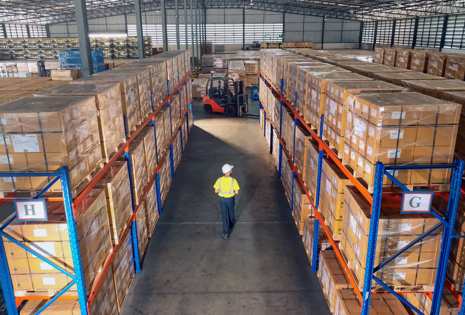 Man walking between warehouse aisles 