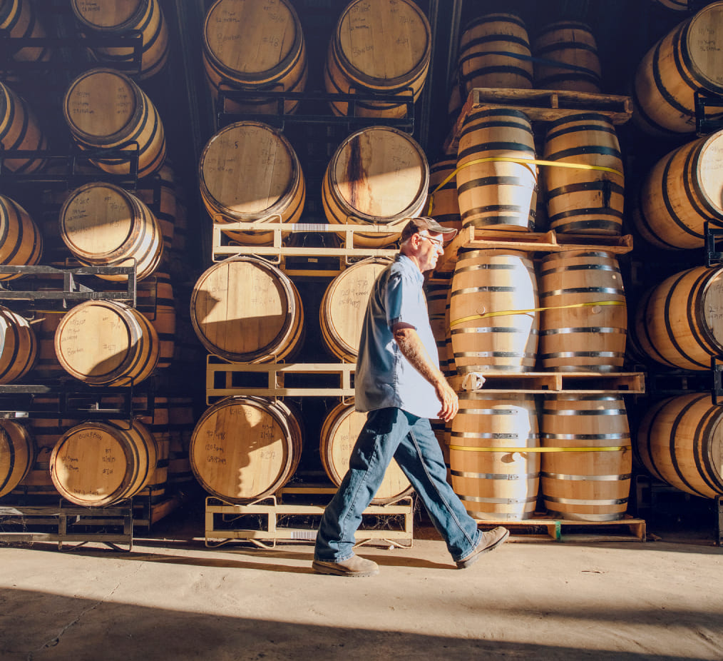 Man walking past wooden barrels