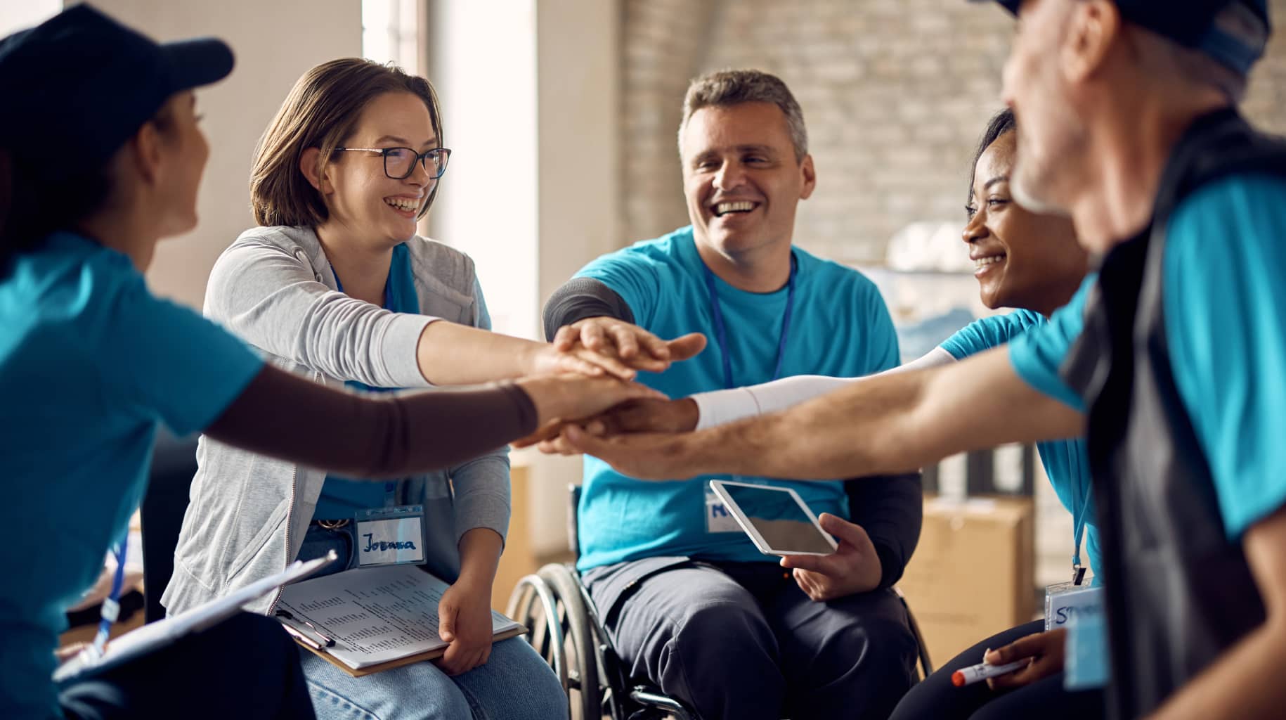 People in wheelchairs stacking hands