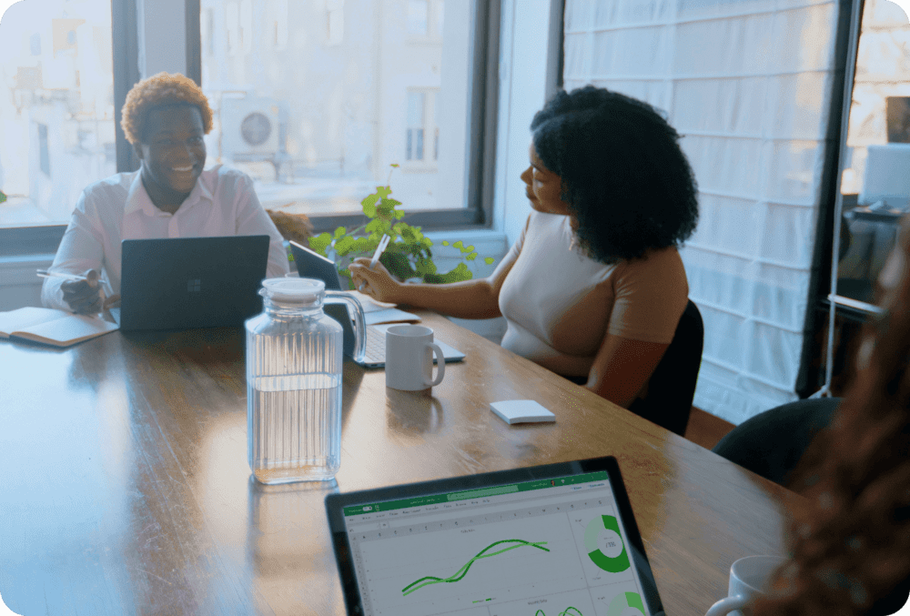 Two woman sitting on a desk looking at graphs on their laptops