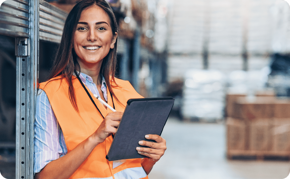 Warehouse woman in high vis smiling and holding a tablet