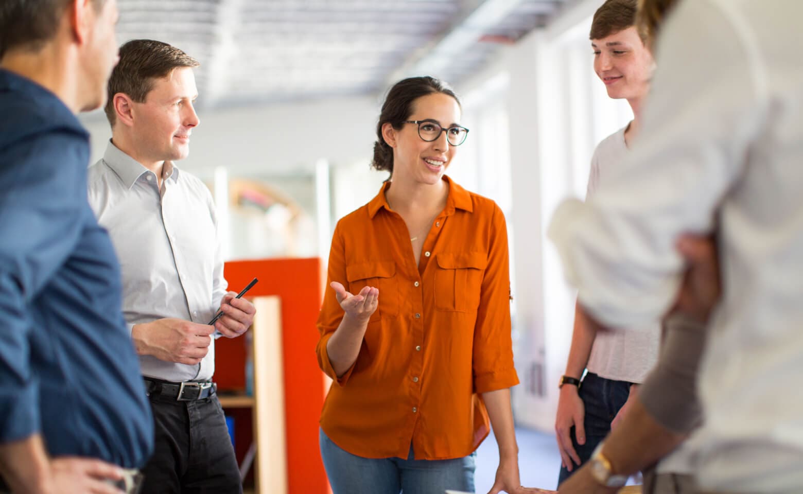 Group of people gathered in a circle with a woman in a red shirt talking