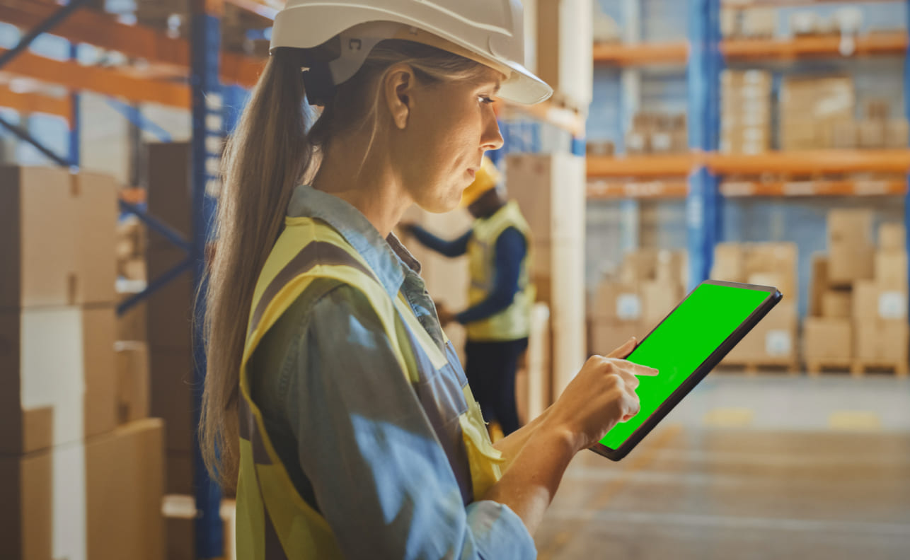 Woman with a green tablet in warehouse