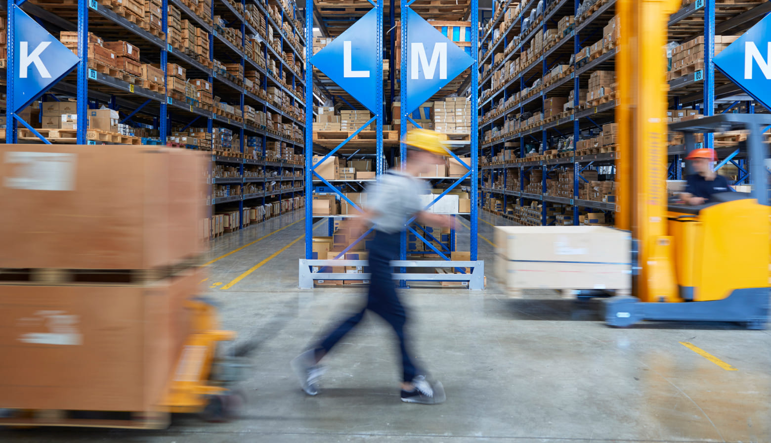 Worker with hard hat running through warehouse